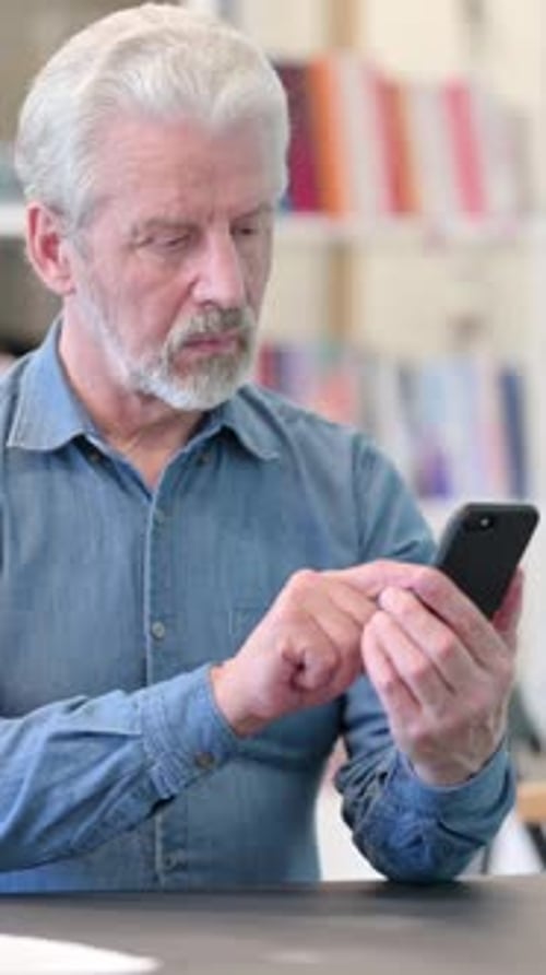 Senior Man Using Mobile Phone Indoors