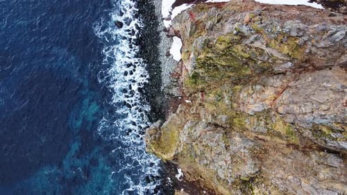 Flying Over Rocky Coastline Alongside Cliffside with Blue North Atlantic Ocean Water at Spring