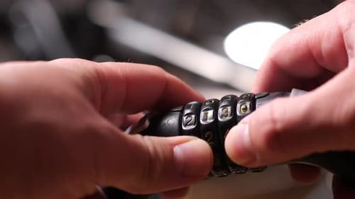Male Hands Hold a Combination Lock with Numbers for a Bicycle Open It Up