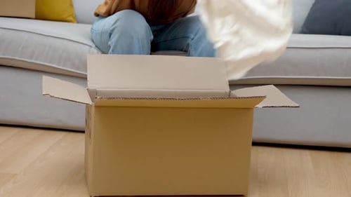 Woman Examines with Interest Colored Dress From Cardboard Box From Online Store with Clothing