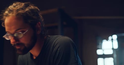 Cabinet maker skillfully cuts lumber on table saw in workshop with warm lighting