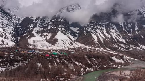 Timelapse of clouds moving over the houses of village amidst mountains in Lahaul