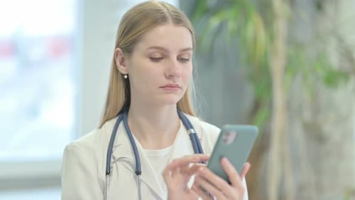 Female Doctor Uses Smart Phone in Hospital Setting
