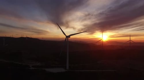 Renewable clean energy from wind farm with windmills. Aerial drone shot of wind turbines at sunset
