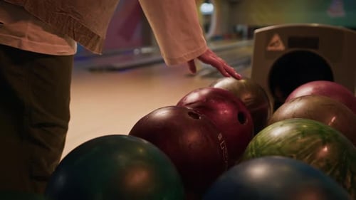 Unbekannter Spieler, der eine Bowlingkugel vom Rack auswählt und einen Wurf macht