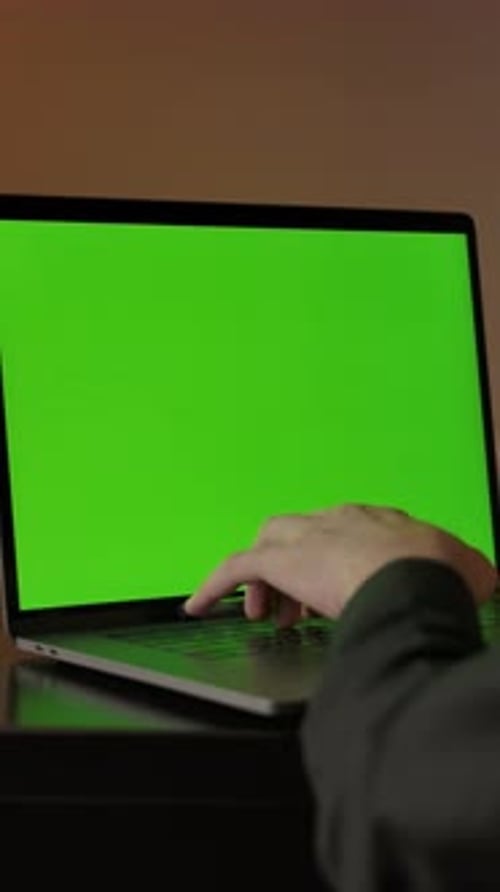 Vertical of Man Typing on Laptop Keyboard with Green Screen Dolly Out Smooth Sliding Shot