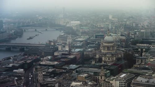 Aerial view showing a cityscape of London; with St pauls and the River Thames in fog.