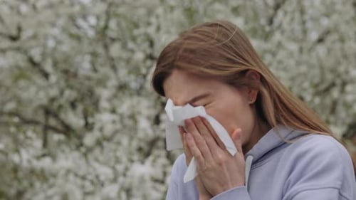 Young Woman with Seasonal Allergies Blowing Nose