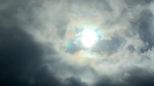 Couleurs brillantes irisées autour du soleil ; prise de vue statique à angle faible regardant les nuages en mouvement.