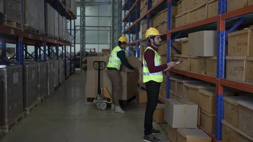 Blue collar workers are working at warehouse.
