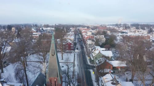 Snowing in small town USA. Lititz, Pennsylvania during winter snow. Rising aerial features steeple a