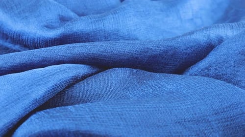 Close-up view of soft folds of dark blue silk muslin rotated on the display case. Textile background
