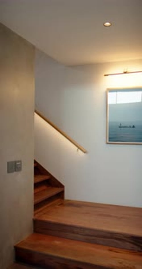 Vertical video: Modern staircase with wooden steps and framed ocean artwork, cozy home decor
