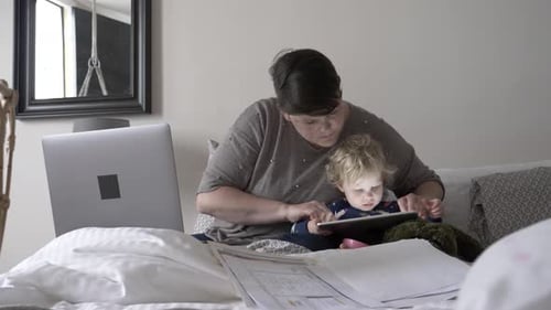 Mother and Toddler Using Tablet on Bed