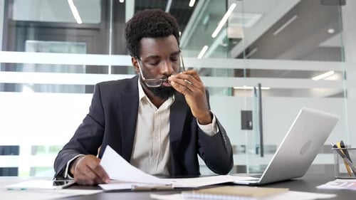 El empresario con exceso de trabajo está cansado de hacer papeleo mientras está sentado en el escritorio en el lugar de trabajo