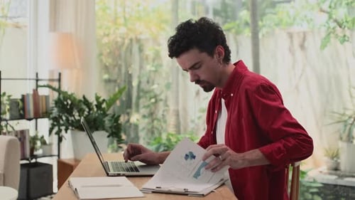 Young Adult Analyzing Data on Laptop at Desk