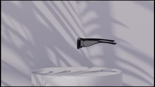 Schwarze sportliche Sonnenbrille, die auf einem weißen Podest mit Palmenschatten schwebt
