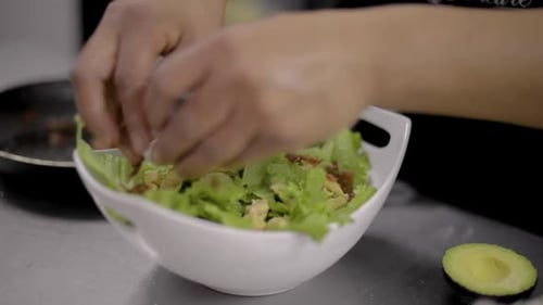 Woman chef cook preparing a salad cutting and adding a chicken breast at a local restaurant diner ca