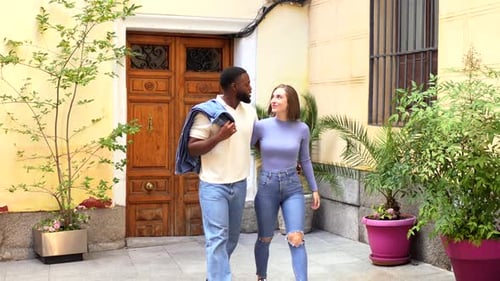 Casal multiétnico saindo de casa abraçado por trás