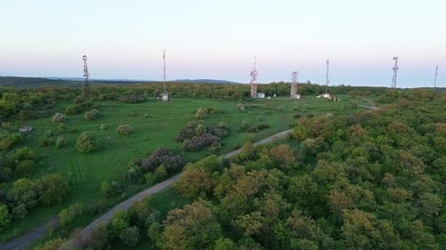View of the Hills Covered with Vegetation with Cell Towers Against the Backdrop of Fields and a