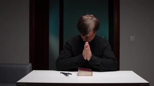 Young Adult Praying at Table at Night