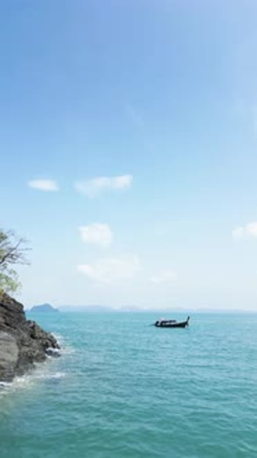 Vertical Video Drone Shot of a Sailboat Near a Tropical Island Shore with Coastal Cliffs