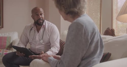Doctor Visiting Senior Patient at Home, Looking at Medical Results on Digital tablet