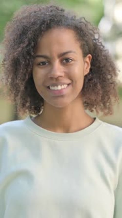 Outdoor Portrait of Smiling Young African Woman Looking at Camera, vertical video