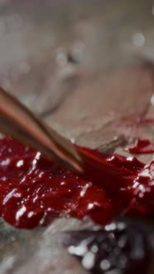 Close Up of Blending Vibrant Red and Burgundy Paints with Brush
