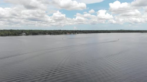 Drone view blue sky white clouds overlooking the water marina speedboat passing by in water sailboat