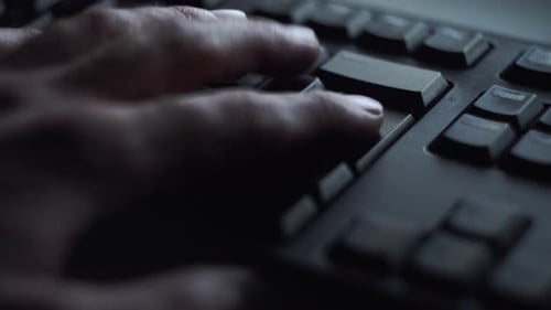 Programmer Typing on a Black Keyboard in the Dark