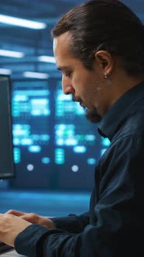 Man Working in Dark Server Room at Night