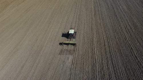 Tractor industrial plowing ground soil in rural agriculture wheat field aerial view