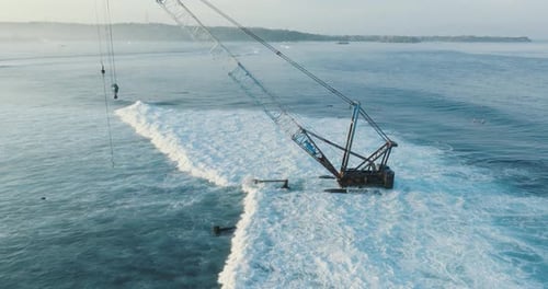 Drone view of Shipwrecks Surf Break with surfers, shipwreck, and waves with Jungutbatu Beach on Nusa