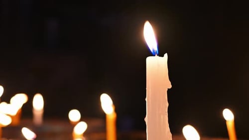 Nahaufnahme einer brennenden Kerze unter vielen brennenden Kerzen
