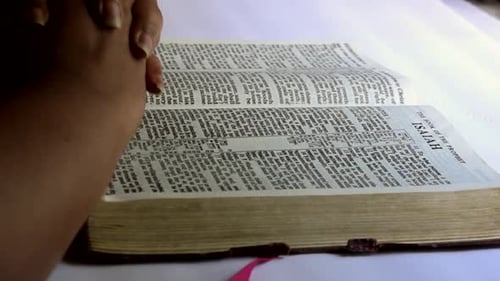 Hands Praying on Bible Book of Isaiah