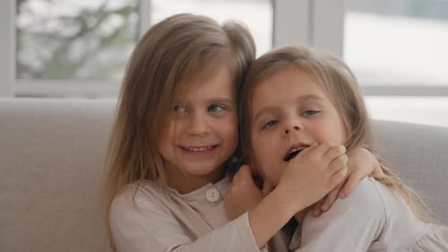 Two Smiling Sisters Hugging Laughing Indoors at Home