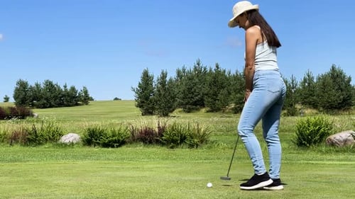 Female golfer use putter club to hit ball into cup, green course in Latvia