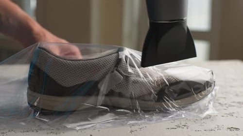 Shoe Shrink-Wrapped Inside Plastic Bag With Hair Dryer