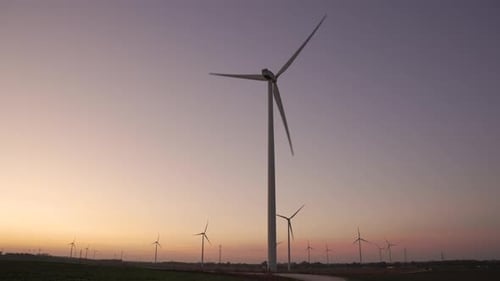 Cinematic shot of Wind Turbine in a large wind farm. Large wind turbine in field against sunset on h