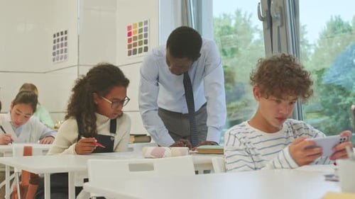Teacher Helping Students with Assignment in Classroom