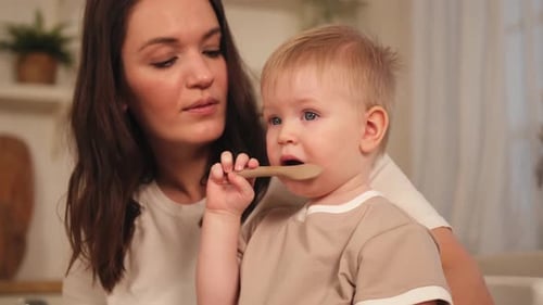 Child Holds Toothbrush with Woman at Home