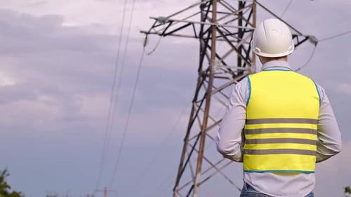 Electrical Engineer Inspecting Power Lines with Tablet