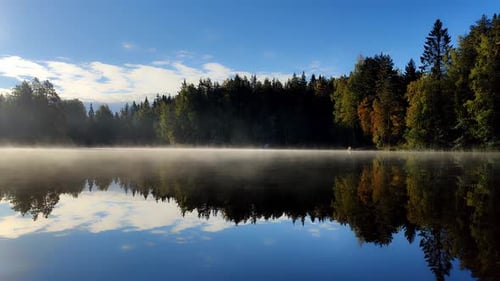 Beautiful lake scenery in Finland. Mist is moving on water surface and sun is rising.