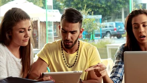 Young multicultural students brainstorming creative ideas at a cafe with technology