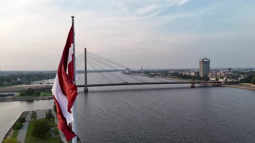 Luftaufnahme der lettischen Flagge, die an einem Fahnenmast in der Hauptstadt Riga bei klarem Sommer weht
