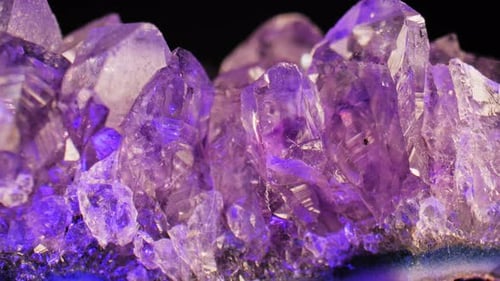 Elegante, flüssige Pfanne aus funkelndem lila Amethystkristall auf einem satten, dunklen Hintergrund. Faszinierend