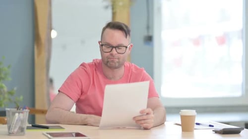 Frustrated Adult Reading Documents at Office Desk