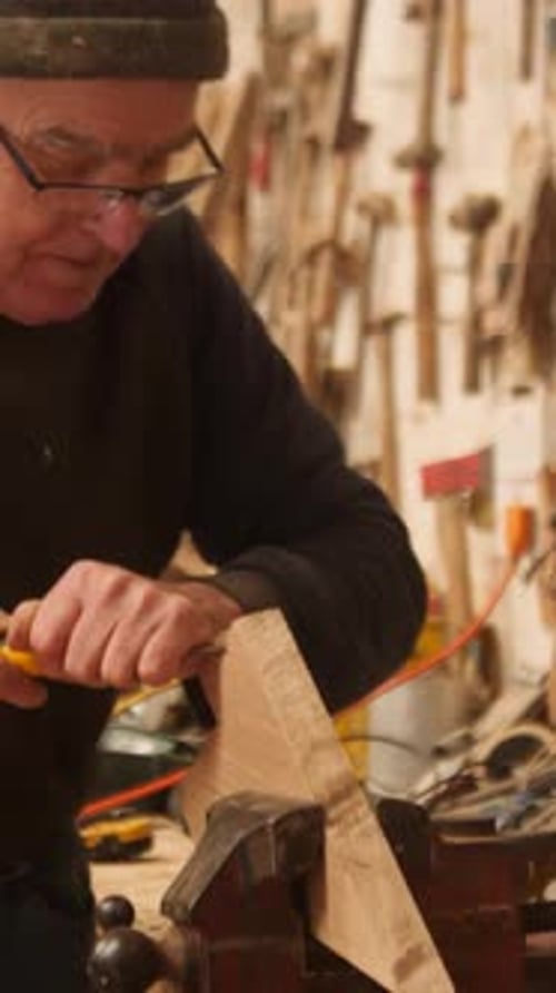 Experienced carpenter shapes oak with chisel