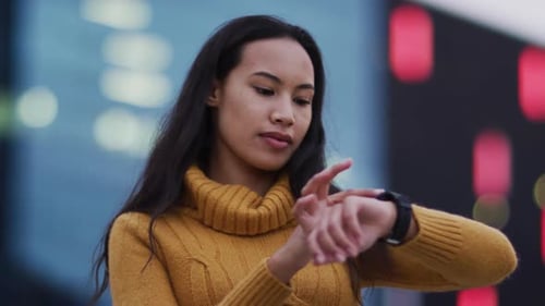 Young Woman Interacting with Smartwatch in City Setting